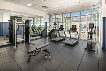 a gym with cardio equipment and a view of the city